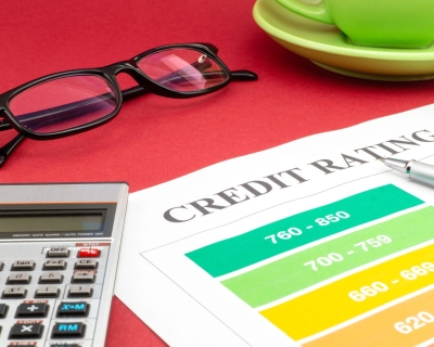 A calculator, pair of glasses, and paper that says credit rating are placed side by side