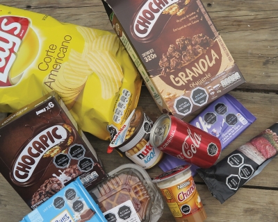 Various products with black octagonal symbols warning against high amounts of sugar, salt, calories or saturated fatty acids lie on a bench. 