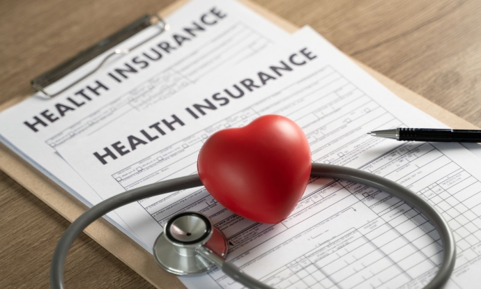 A stethoscope placed on top of a health insurance form